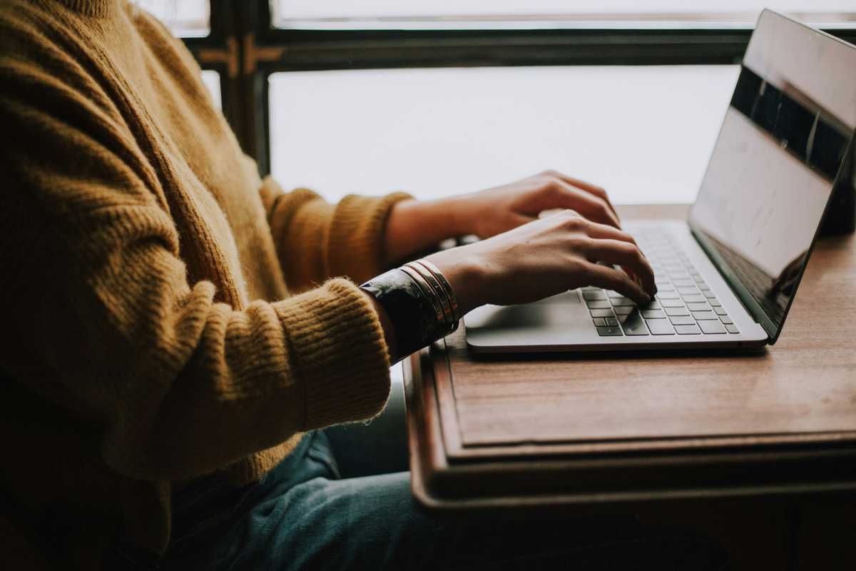 Hands typing on a laptop, filling in an online application