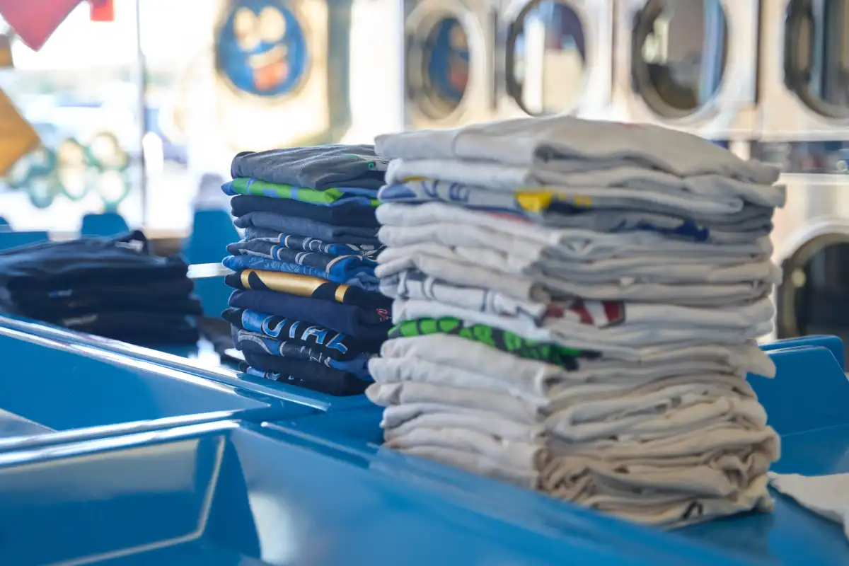 Stacks of neatly folded clothes on a laundromat counter