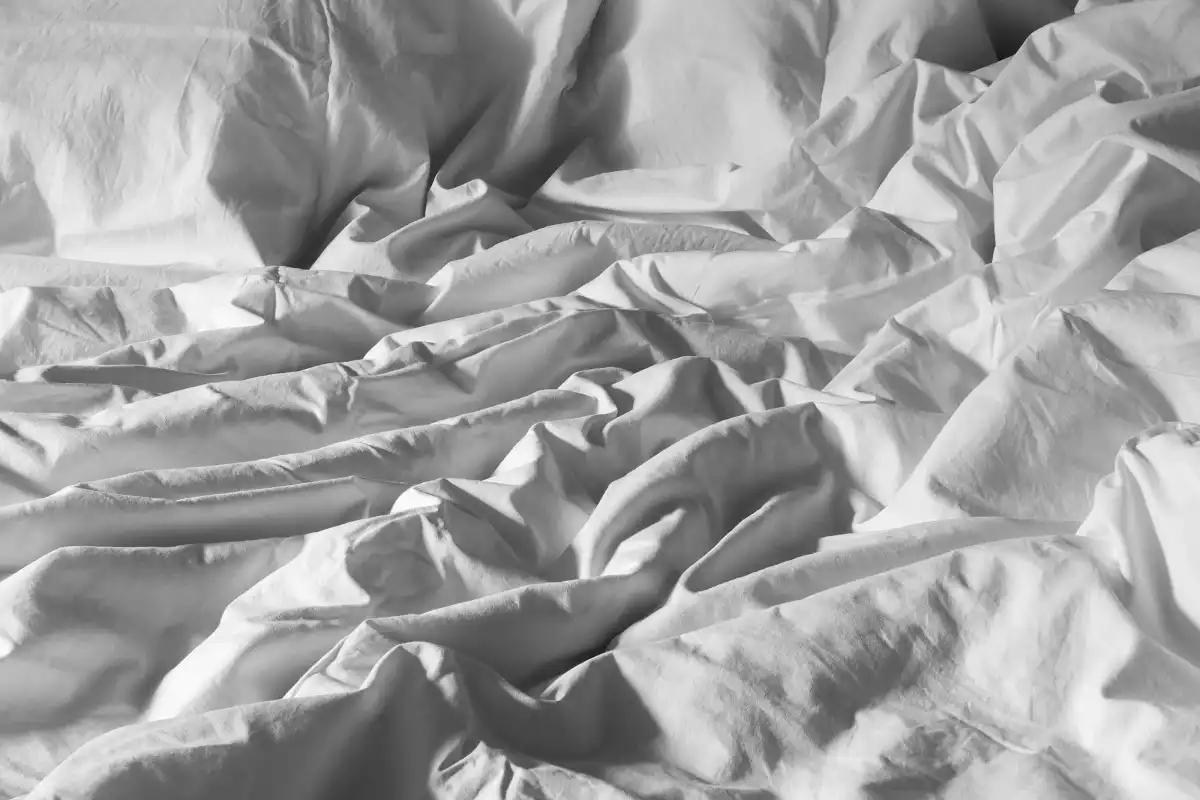 A rumpled white duvet in a cotton cover on a bed