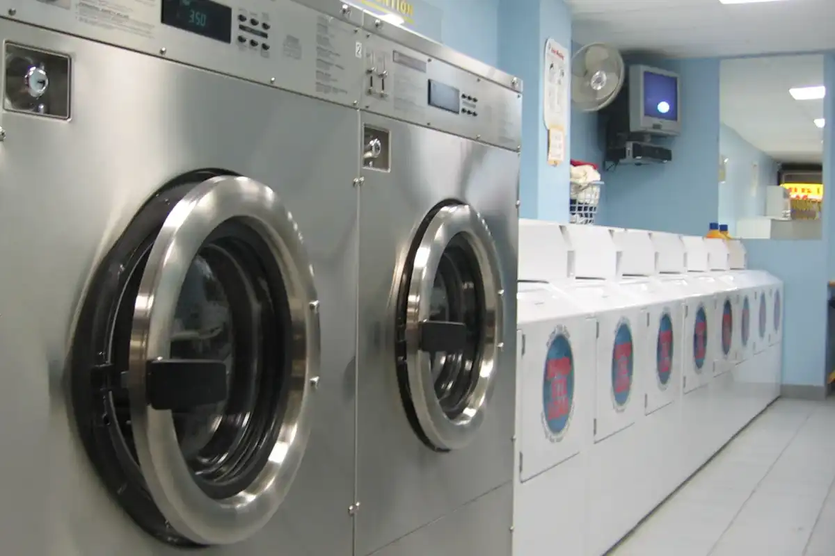 Stainless steel front-loading washers beside a row of top-loaders in an Ontario laundromat